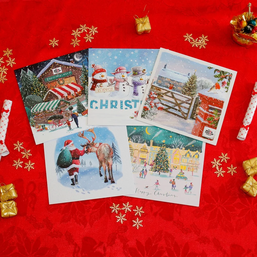 The Brain Tumour Charity Christmas Card collection on red with gold presents around it