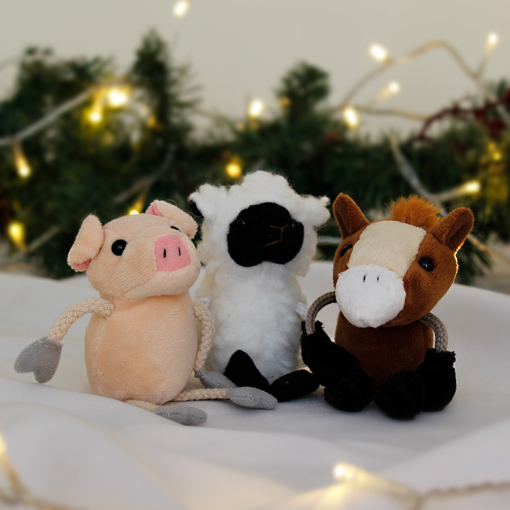 A pig, sheep, and horse finger puppet surrounded by Christmas lights